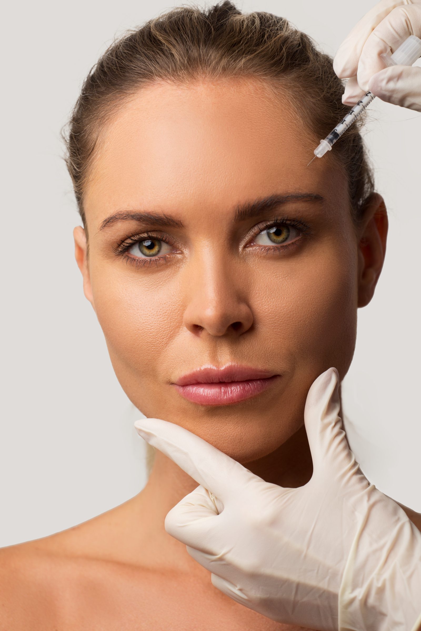 Gloved hands with a syringe beside the brow