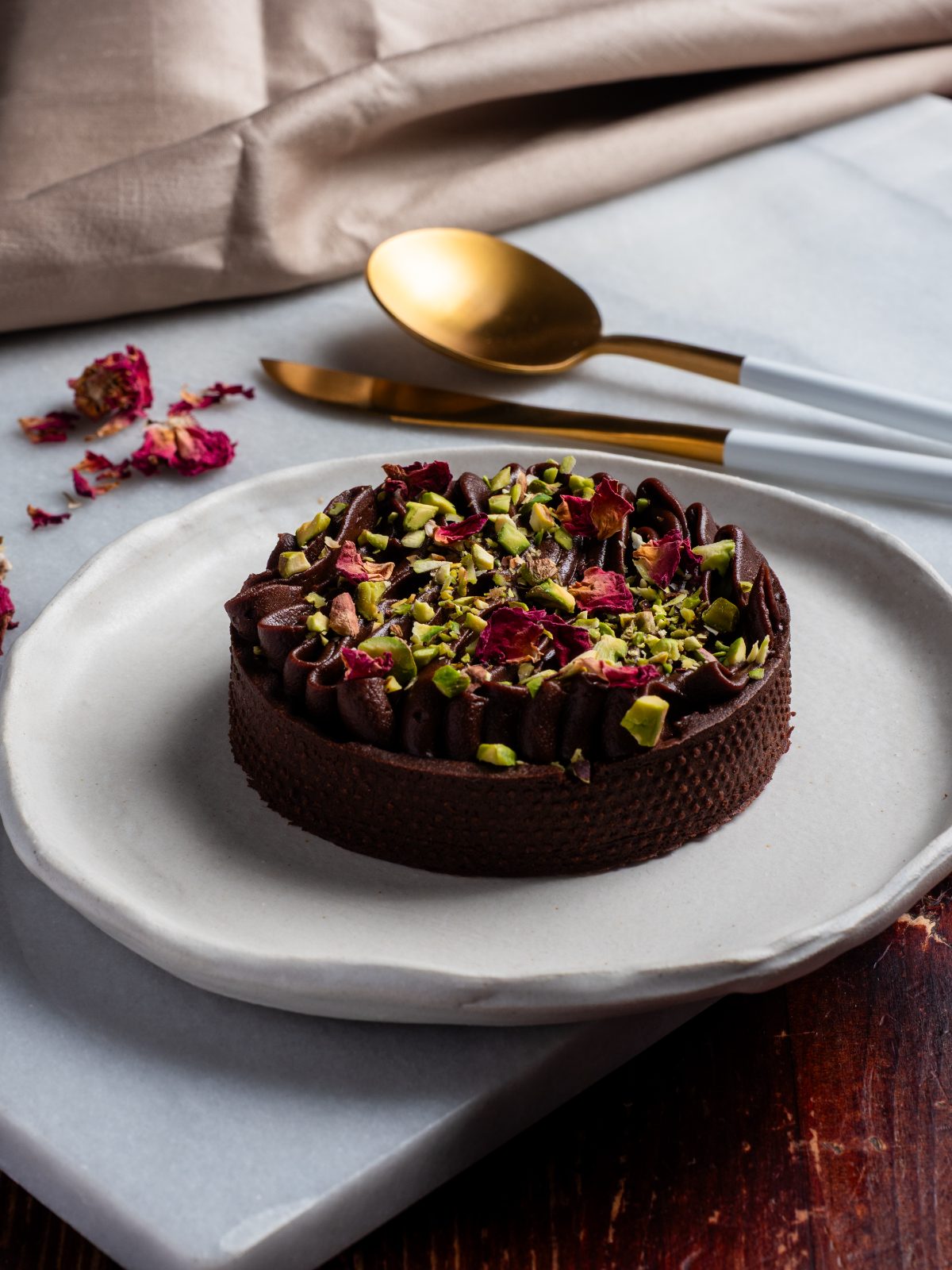 Chocolate and pistachio tart on a pale plate