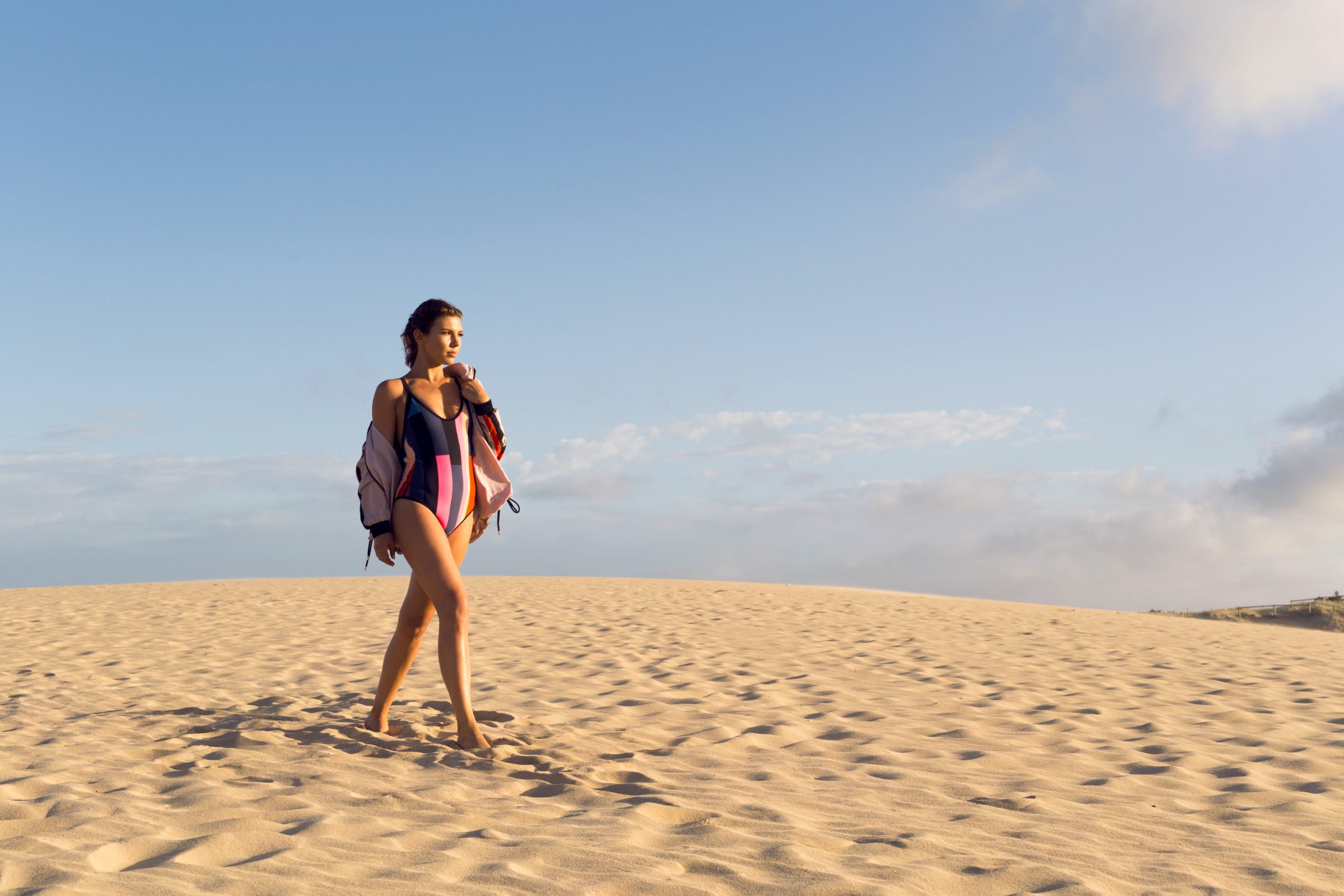 Swimsuit and jacket on the sand dunes at sunrise