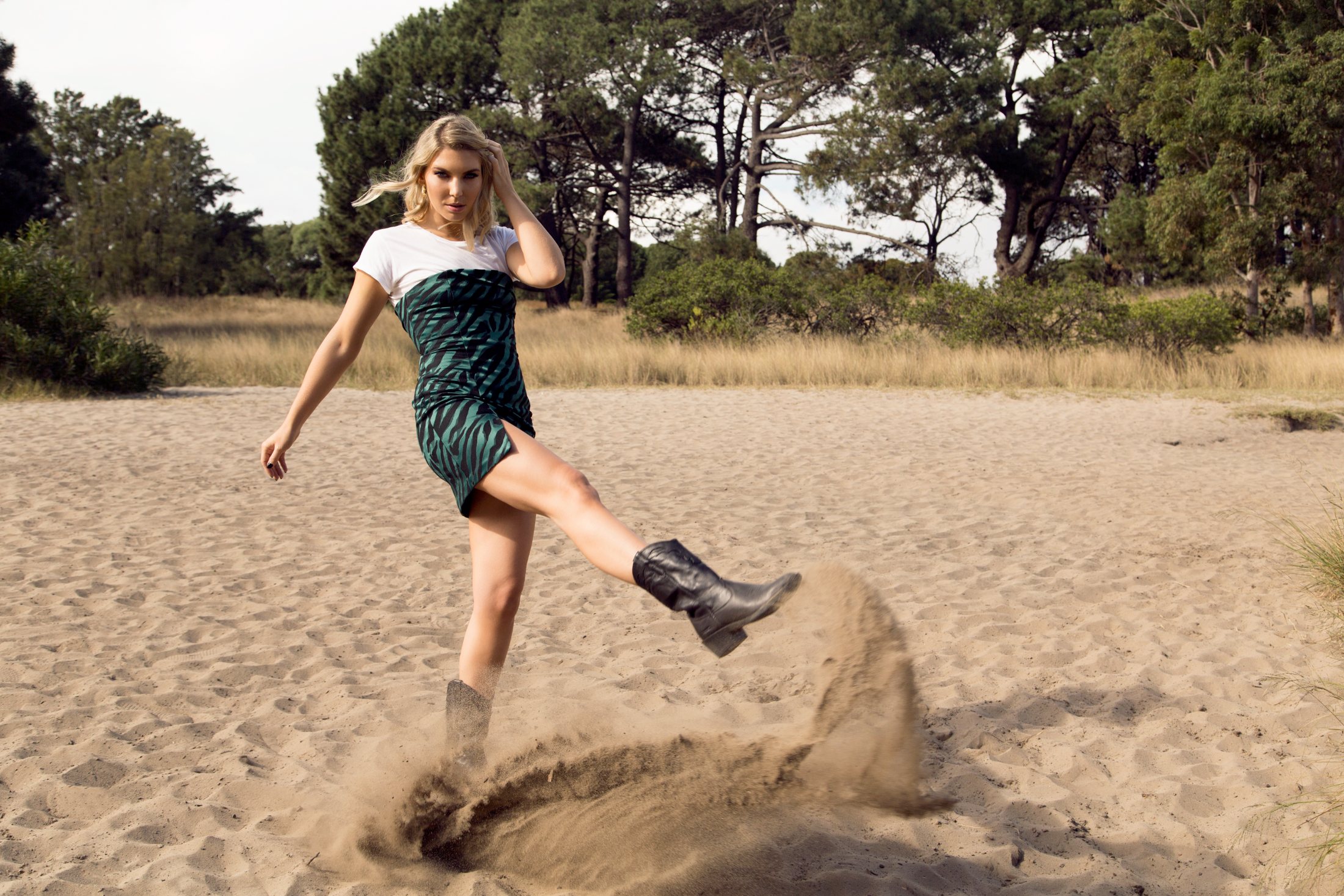 Green printed dress and boots kicking up sand