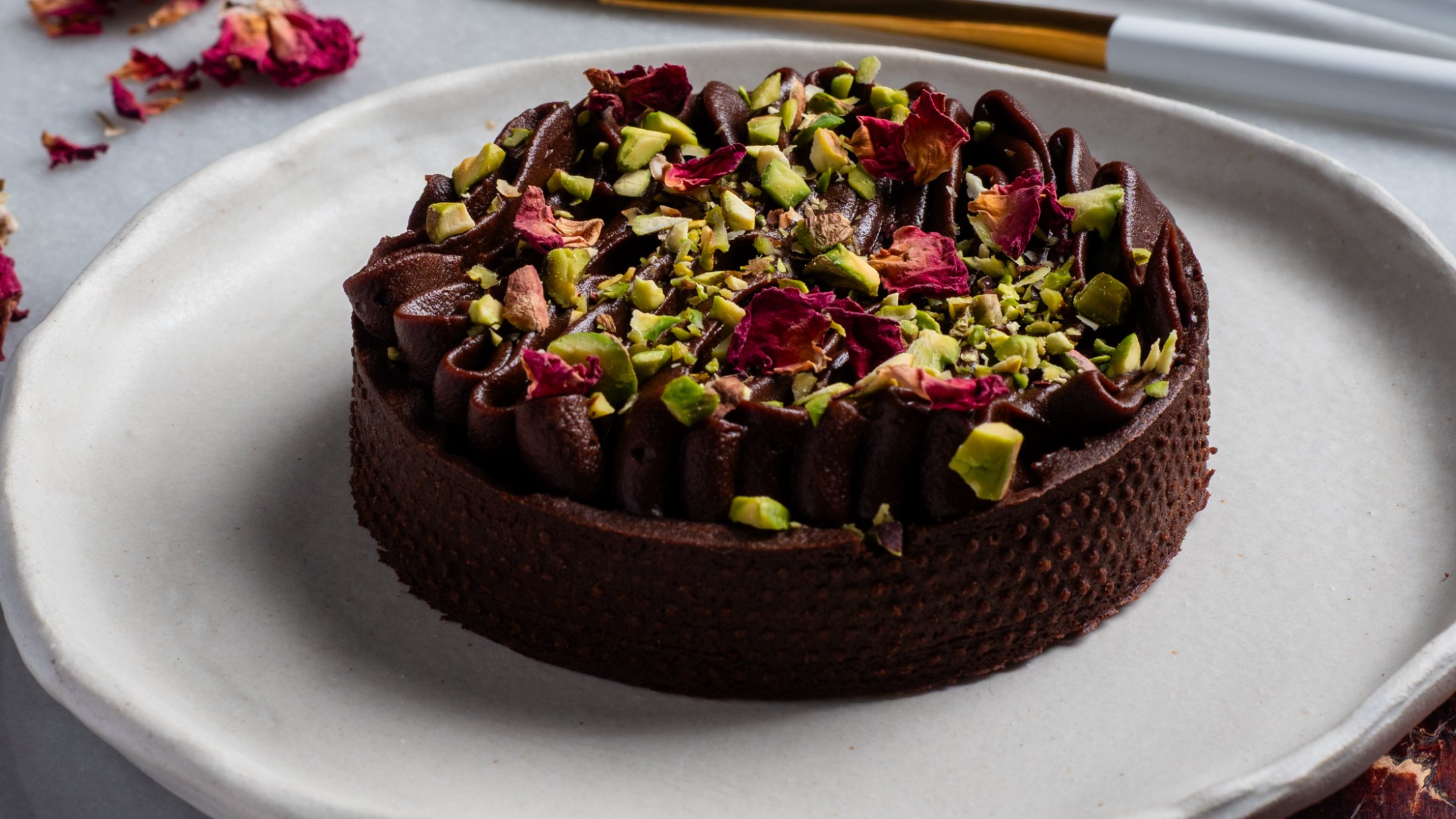 Chocolate and pistachio tart on a pale plate